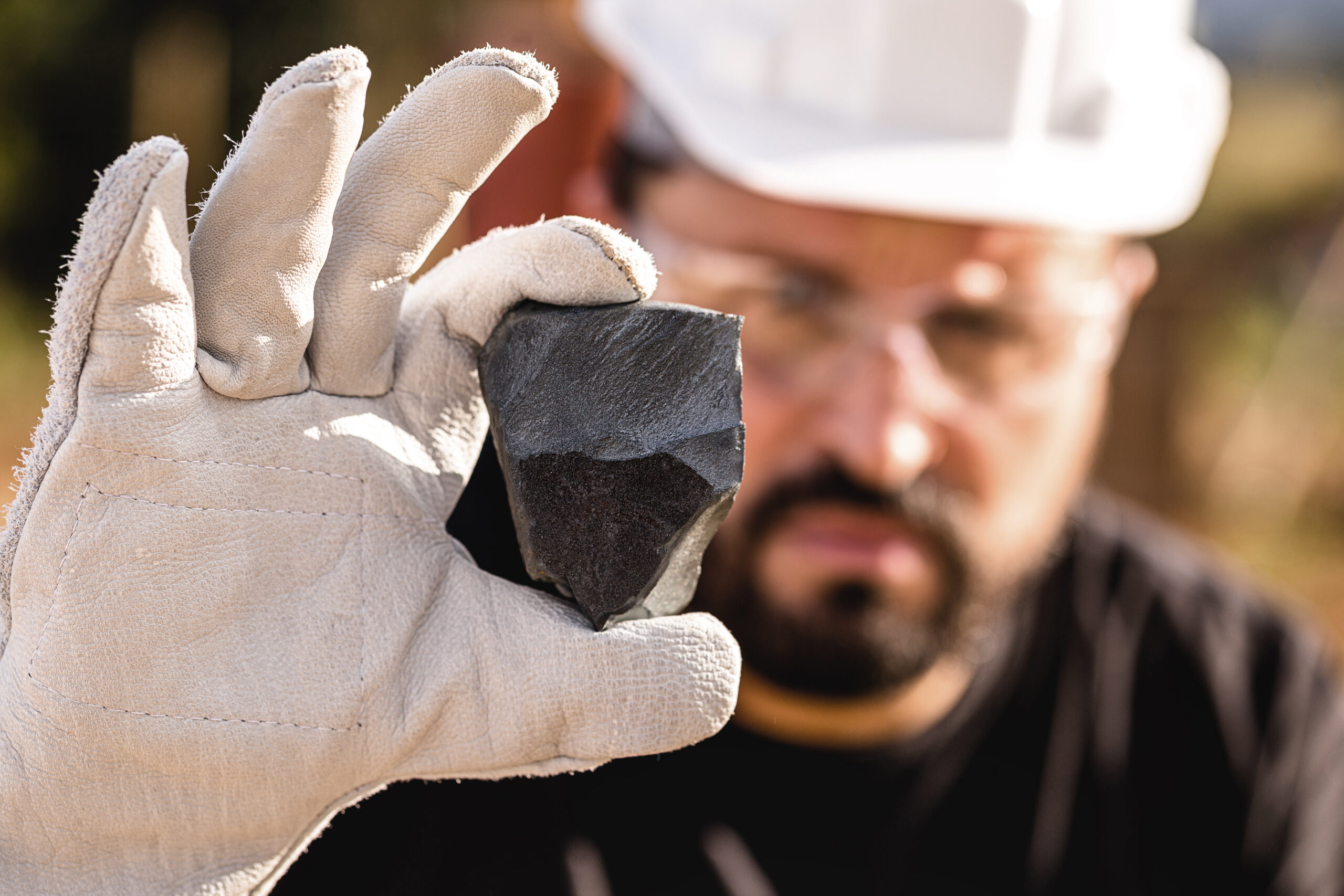 rough iron stone, ferrous metal nugget mined. Miner holding hematitia stone. Spot focus.